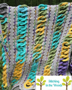 A blanket with colorful rings is draped on the back of a chair. It's a pregnancy temperature blanket with the rings each representing a day's temperatures for a full pregnancy.