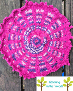 Finished fair isle style Fiore washcloth lies on a wooden deck