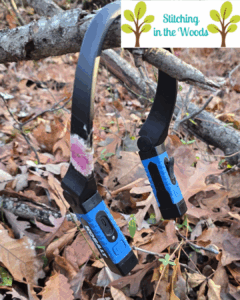 a Kobalt neck light with a flower sticker hangs on a stick with a leaf-littered background; Kobalt is a Lowe's brand