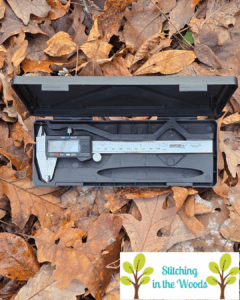 a set of calibers sit in their box with a layer of leaves in the background